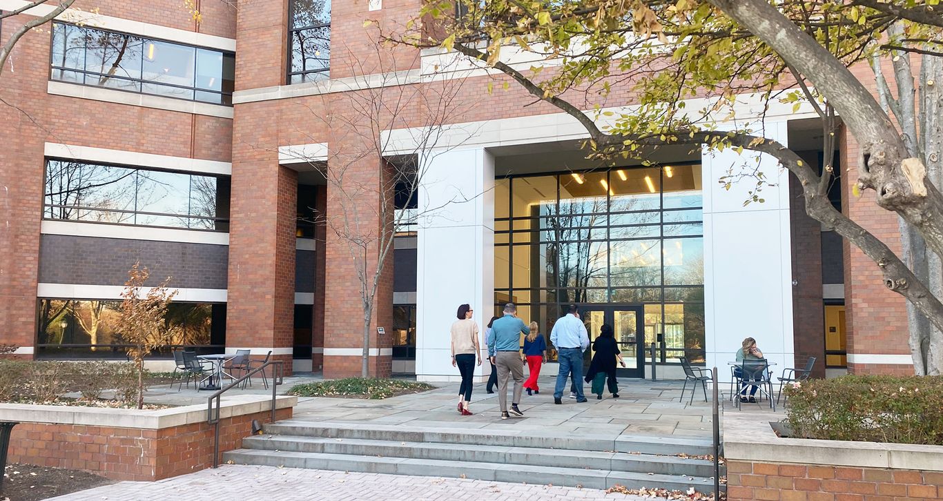 People walking towards the entrance of Camurus Inc building with large windows and trees in the foreground.