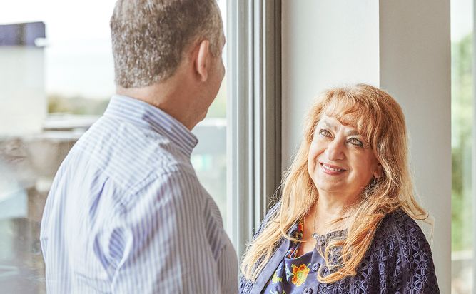 Two Camurus employees standing indoors by a window, engaging in a conversation. 